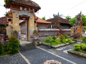 the entry to a family compound in a village in Bali; entry is on the left, on the right are gardens which line the road; toilets are a new addition to village homes in Bali
