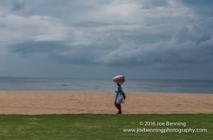 Woman balancing packages on her head while walking on the beach