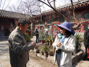 the owner of the Hutong house talks with a guest from the ship in the courtyard/quadrangle