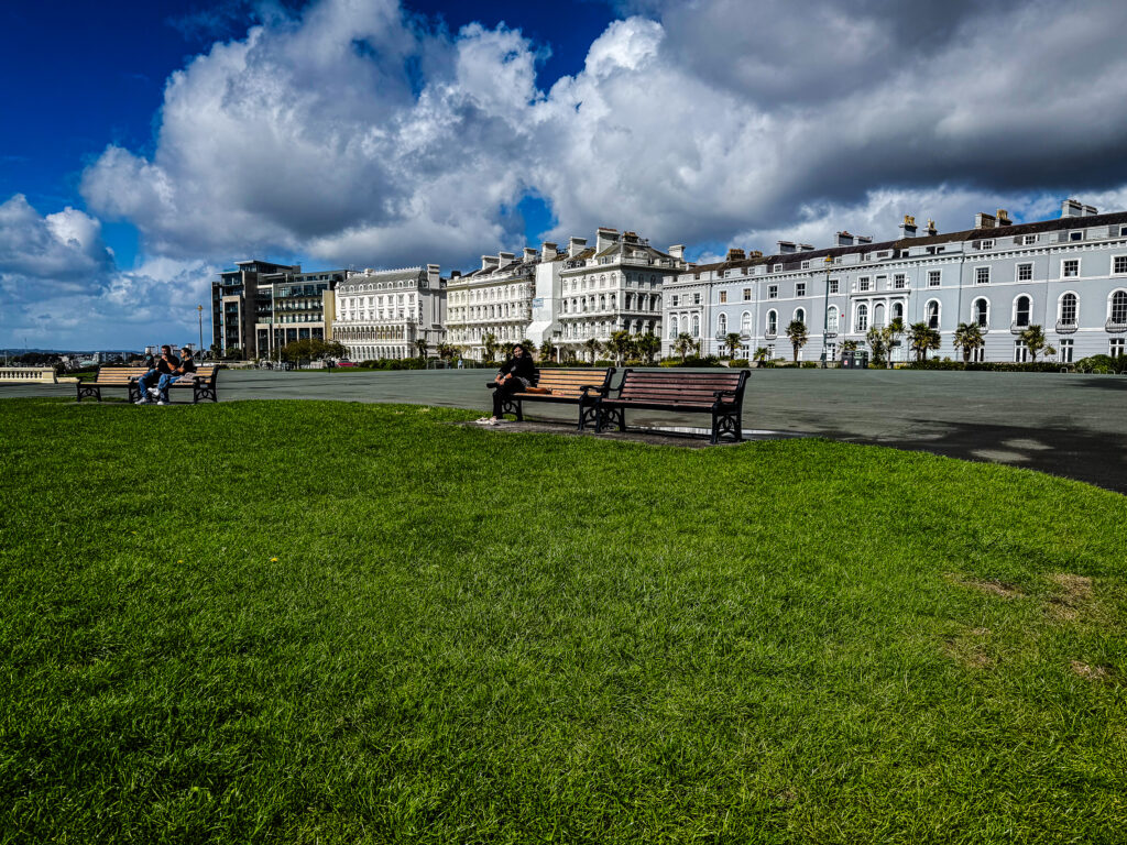 White buildings of Elliot Terrace beside the green lawn of Plymouth Hoe in Devon, England.