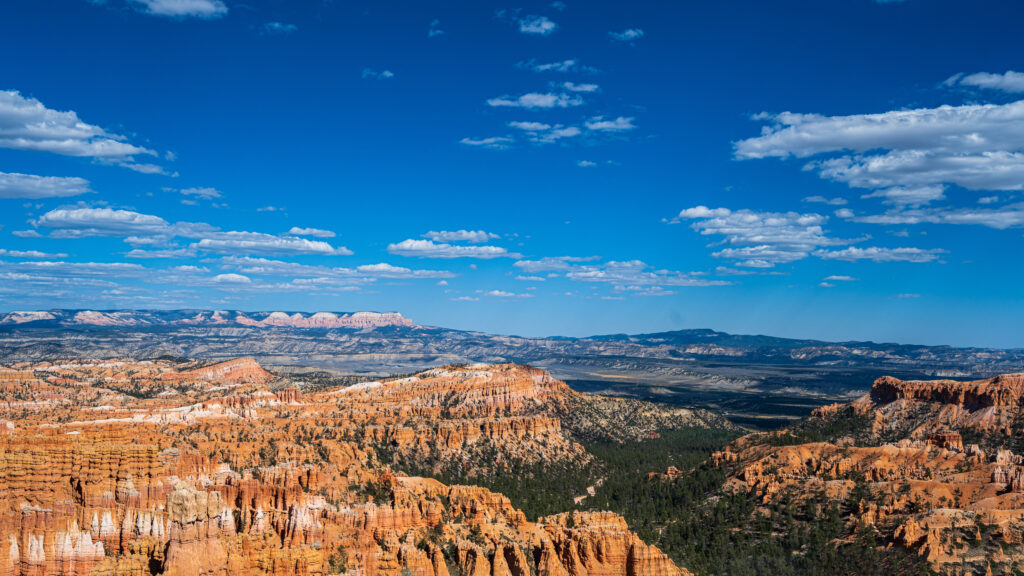 Bryce Canyon Hoodoo Panorama Under a Blue Utah Sky Rows of orange hoodoos fill a broad amphitheater beneath scattered white clouds.