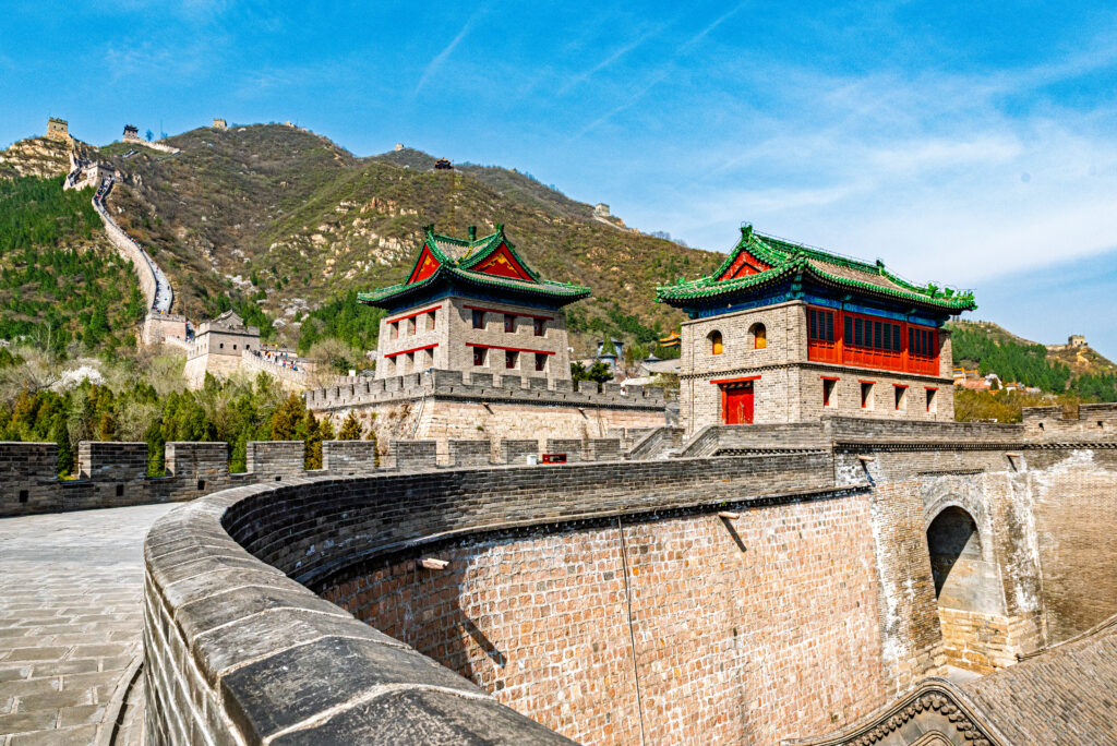 Green-roofed gate towers rise above curving stone ramparts at the Great Wall near Beijing, China.
