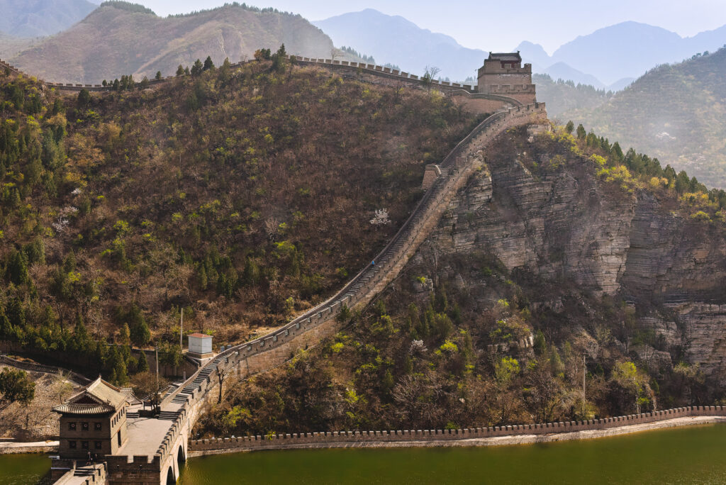 Stone watchtowers punctuate a Great Wall ridge above layered mountains near Beijing, China.