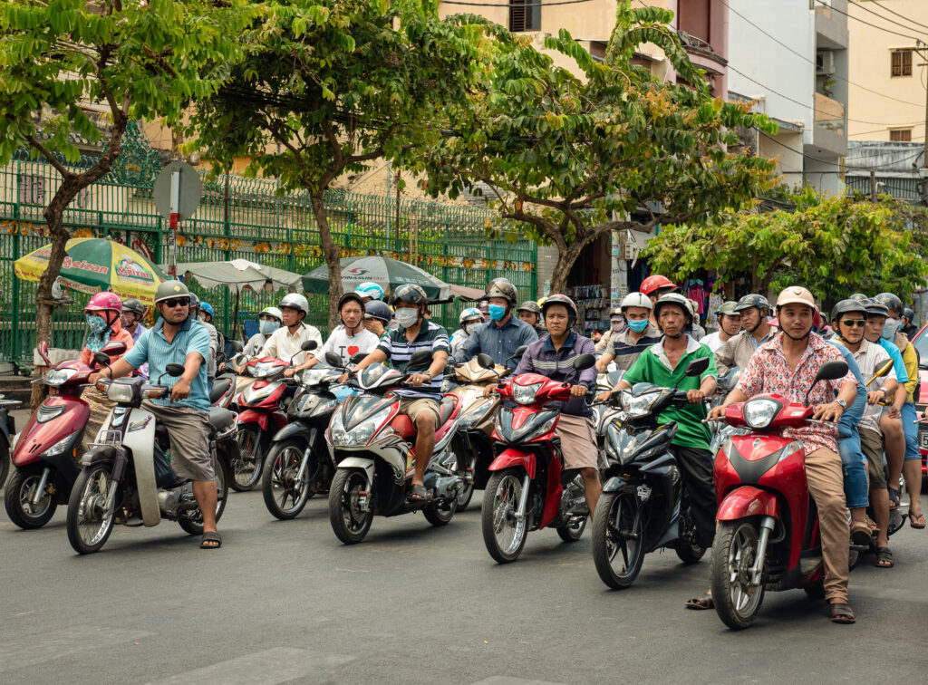 Helmeted motorcyclists fill a city street in Ho Chi Minh City, Vietnam