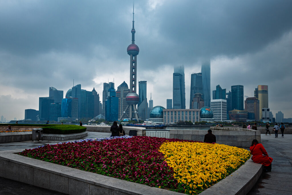 Flower beds frame the Pudong skyline and Oriental Pearl Tower across the Huangpu River in Shanghai, China.