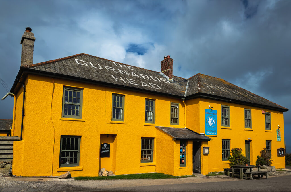 Yellow facade of Penlee House Gallery & Museum beneath dramatic clouds in Penzance, Cornwall, England.