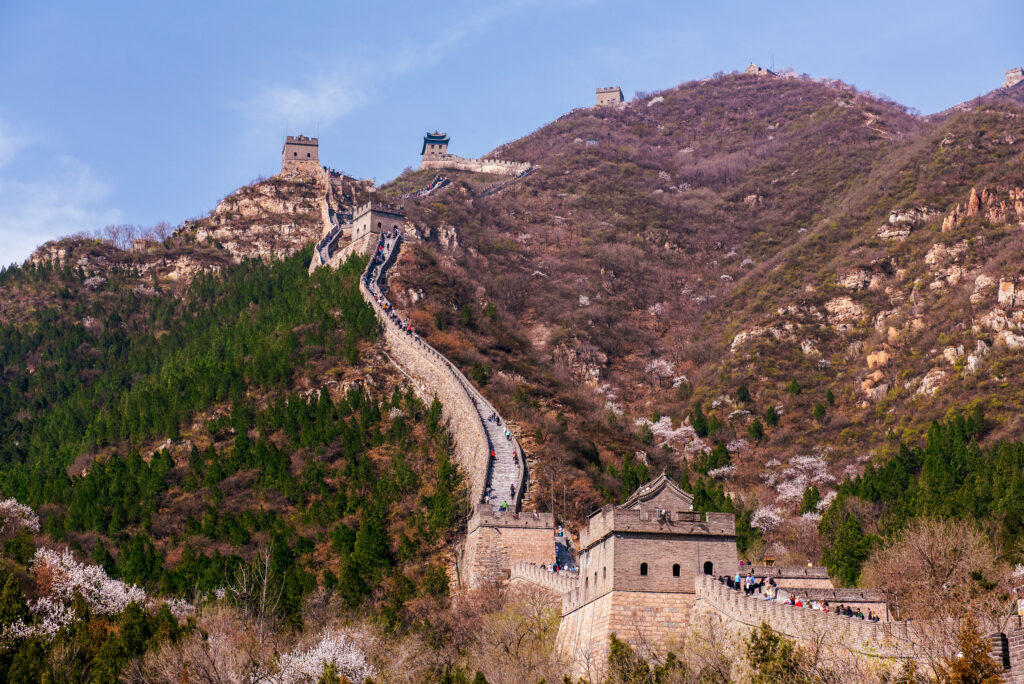 Visitors climb the Great Wall as it rises through flowering mountain slopes near Beijing, China.