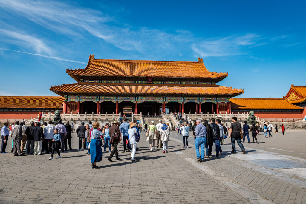 Groups of visitors gather before a golden-roofed palace hall in Beijing&rsquo;s Forbidden City.