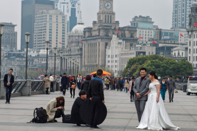 A couple in formal attire poses for a photo session on the Bund promenade in Shanghai, China.