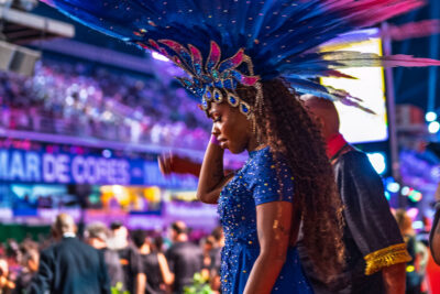 A Carnival performer in Rio de Janeiro wears a blue costume and an expansive blue and pink feathered headdress.
